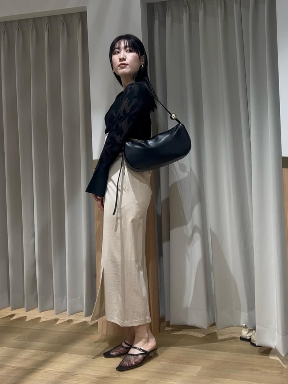 ブラック系のニット/セーター、ベージュ系のスカート、ブラック系のサンダルを着用したレディースの春コーディネートの2枚目の写真