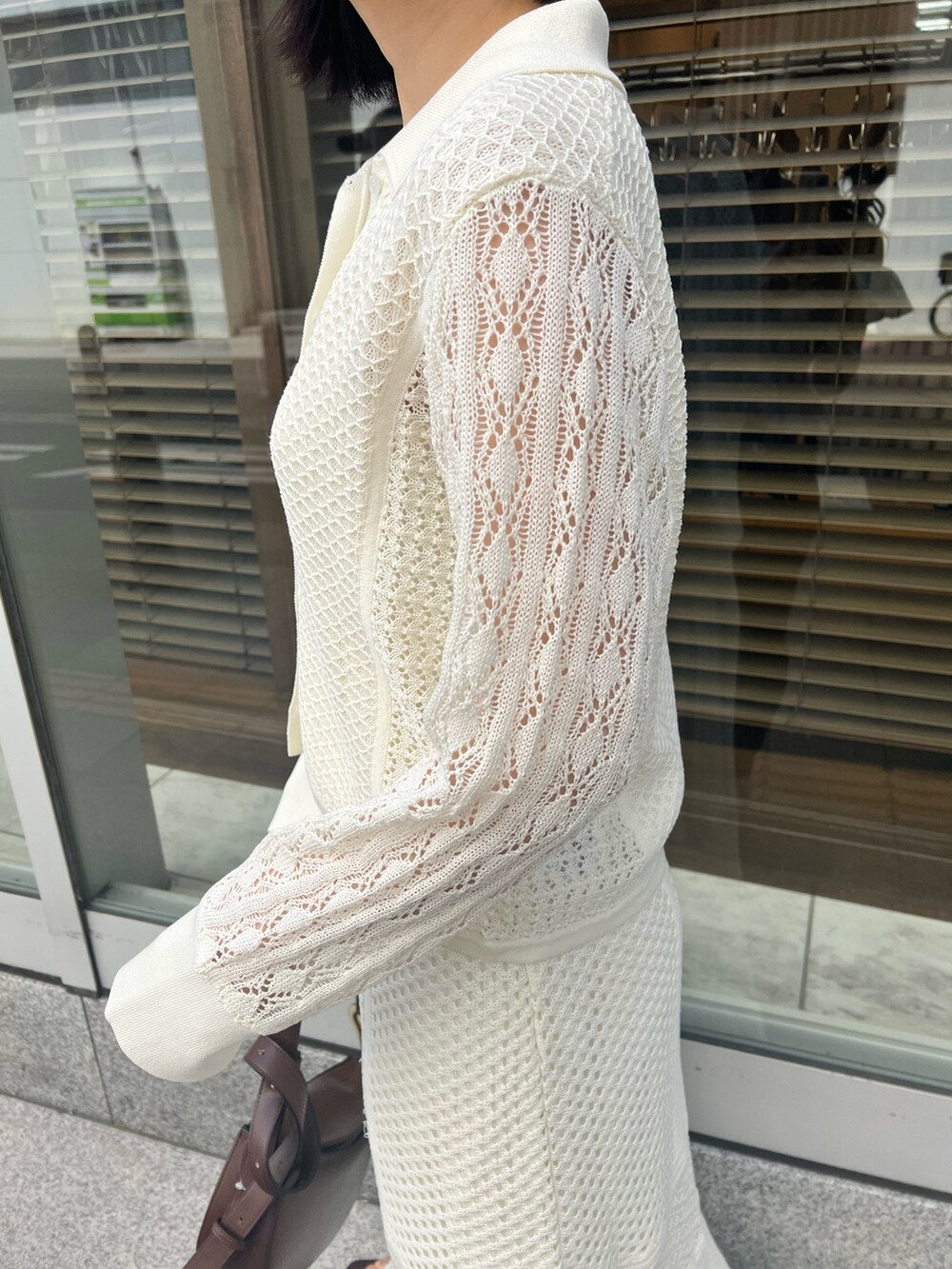 ブラウン系のショルダーバッグ、ホワイト系のカーディガン/ボレロ、ホワイト系のTシャツ/カットソーを着用したレディースの春コーディネートの7枚目の写真