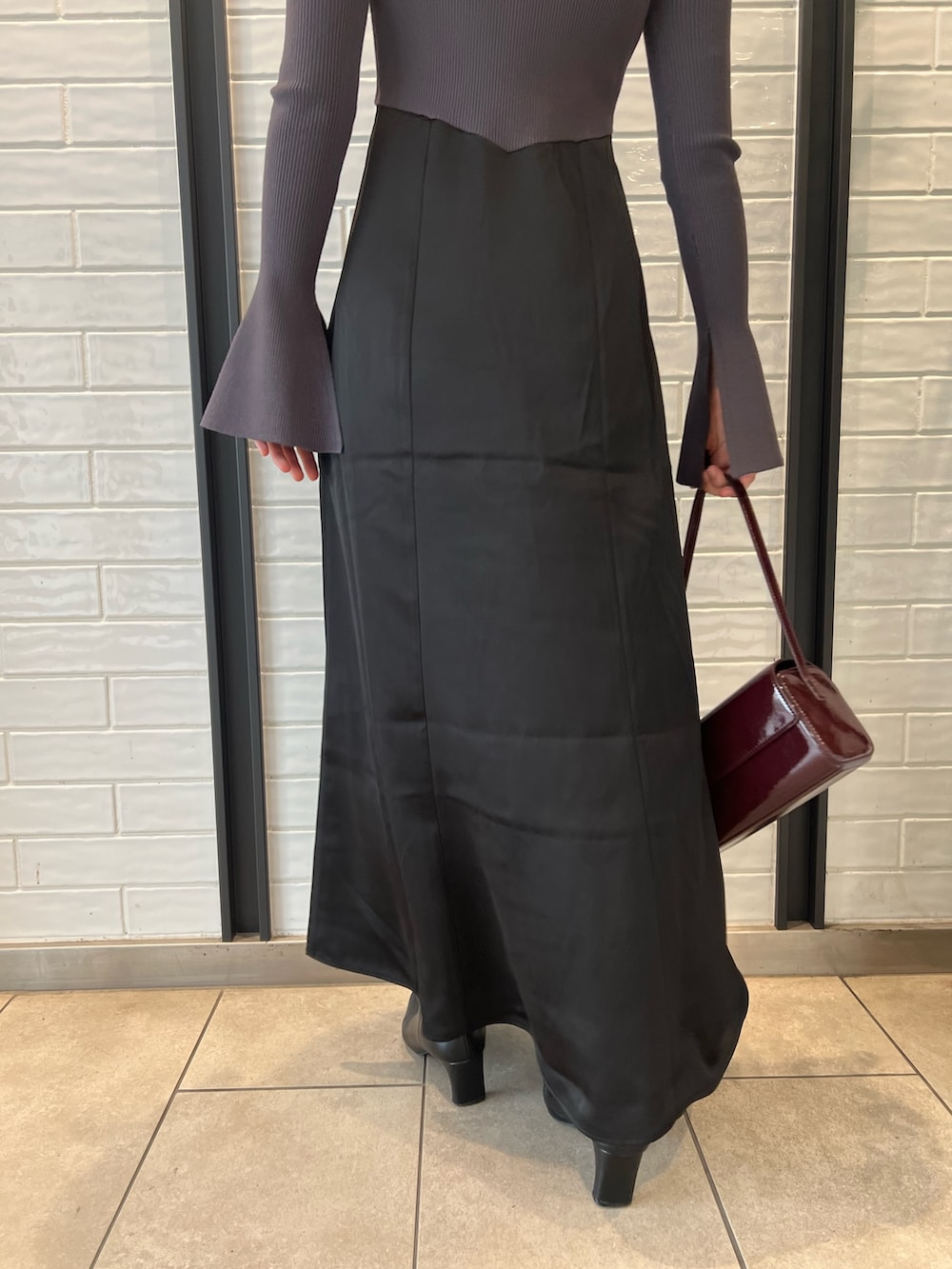 レッド系のショルダーバッグ、ブラック系のブーツ、グレー系のワンピースを着用したレディースの秋コーディネートの8枚目の写真