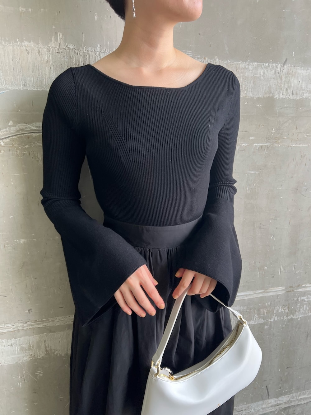 ホワイト系のハンドバッグ、ブラック系のワンピース、ブラック系のパンプスを着用したレディースの秋コーディネートの4枚目の写真