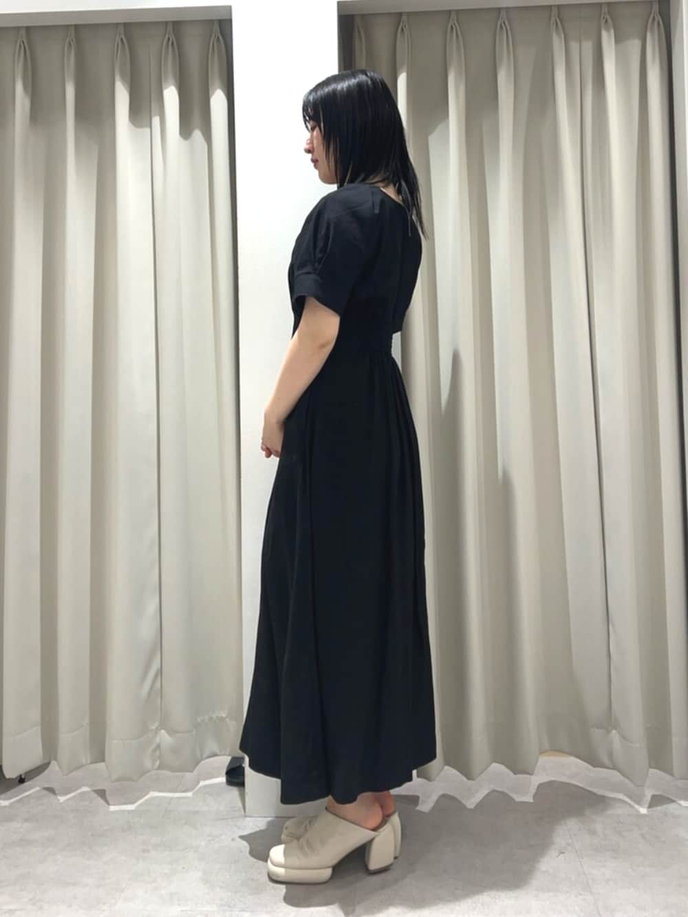 ホワイト系のサンダル、ブラック系のワンピースを着用したレディースの春コーディネートの2枚目の写真