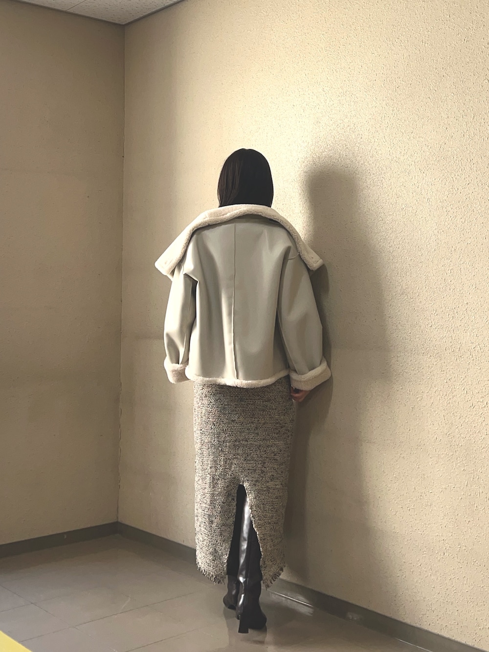 ブラウン系のブーツ、ホワイト系のムートンコート、ベージュ系のジャンパースカートを着用したレディースの秋コーディネートの3枚目の写真