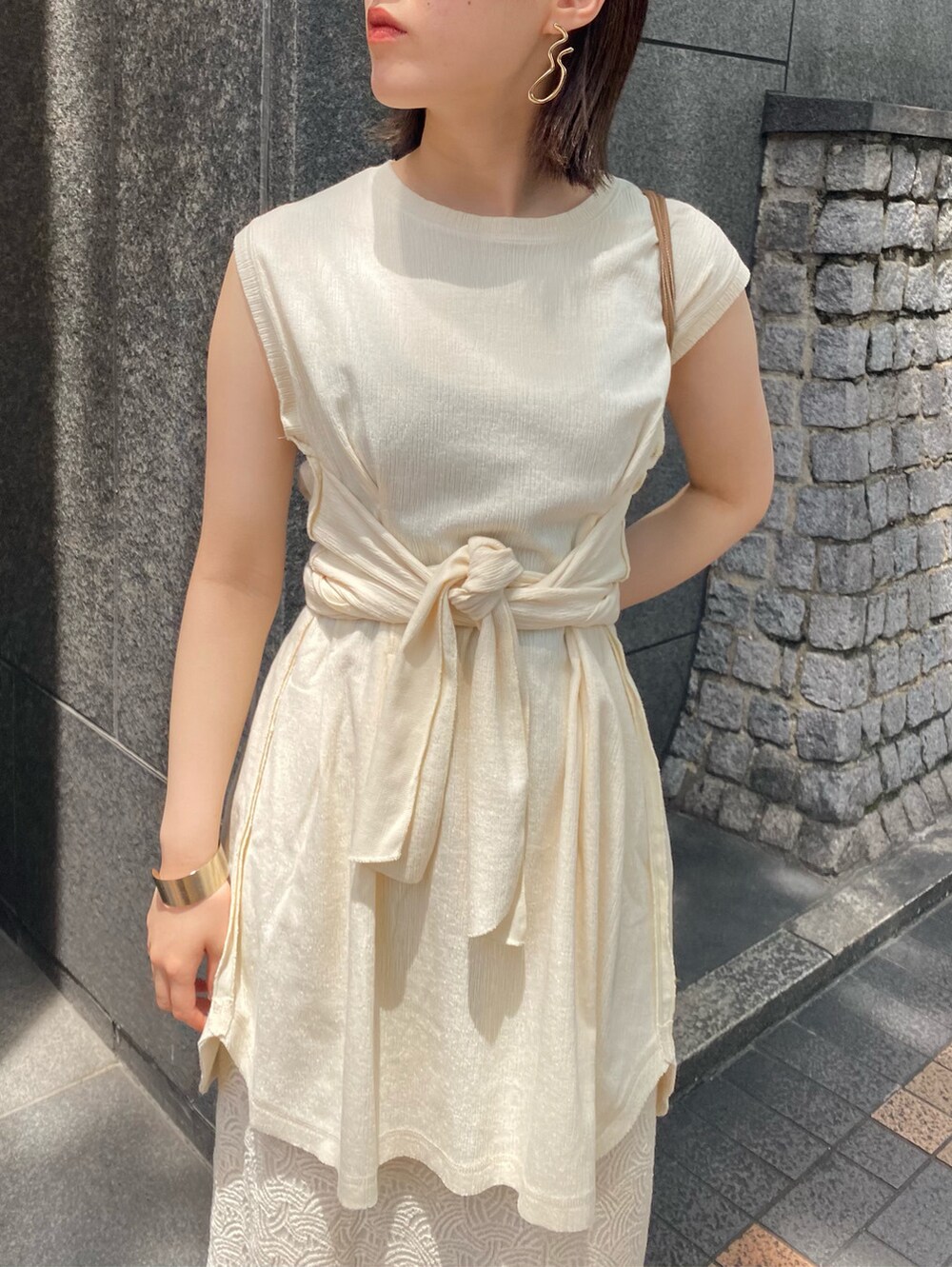 ベージュ系のショルダーバッグ、ホワイト系のスカート、ブラウン系のサンダルを着用したレディースの夏コーディネートの3枚目の写真