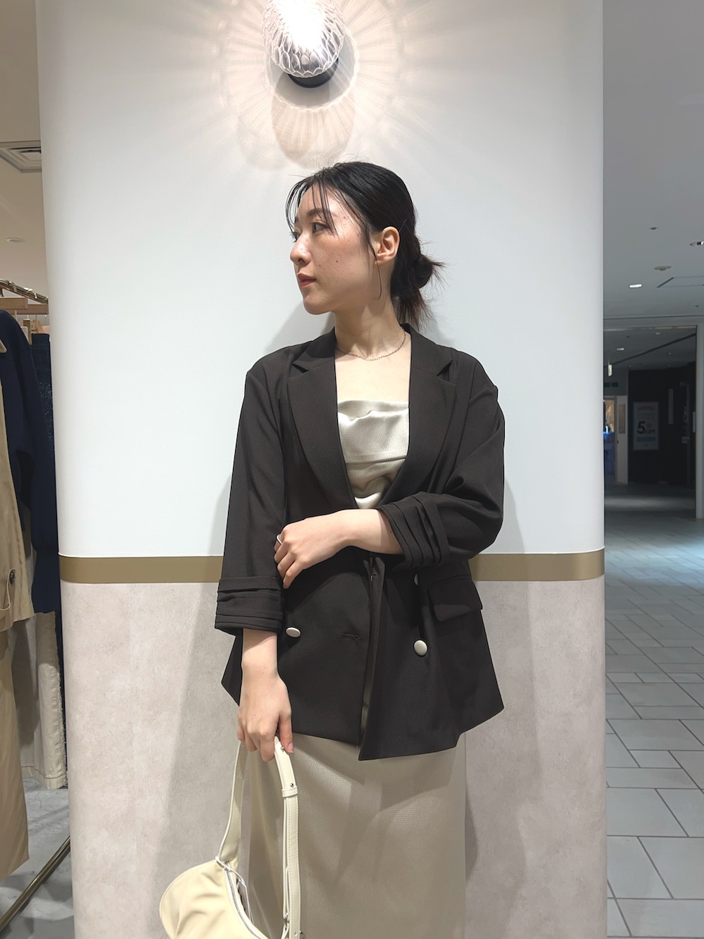 ベージュ系のワンピース、ブラウン系のテーラードジャケット、グリーン系のパンプスを着用したレディースの春コーディネートの3枚目の写真