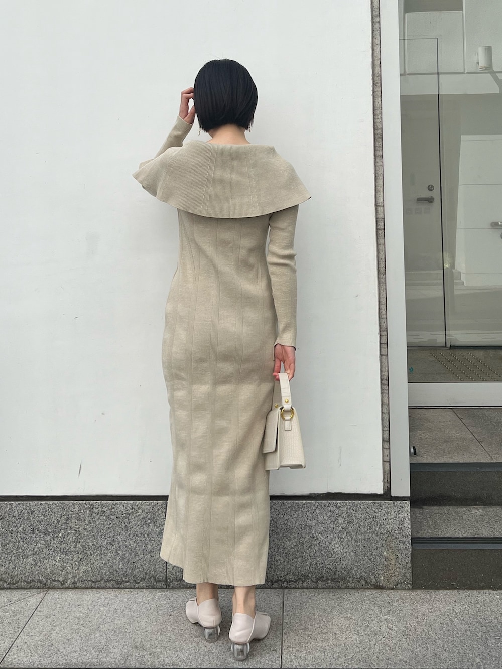 ホワイト系のパンプス、ベージュ系のワンピース、ホワイト系のショルダーバッグを着用したレディースの春コーディネートの2枚目の写真