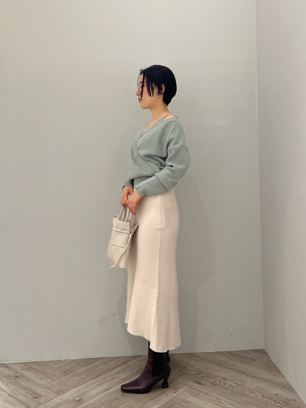 レッド系のブーツ、ホワイト系のハンドバッグ、ホワイト系のスカートを着用したレディースの冬コーディネートの2枚目の写真