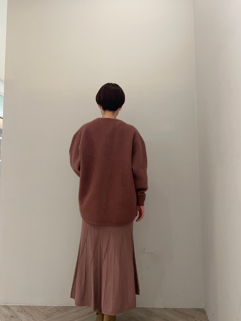 ピンク系のカーディガン/ボレロ、ピンク系のワンピース、ベージュ系のブーツを着用したレディースの秋コーディネートの2枚目の写真