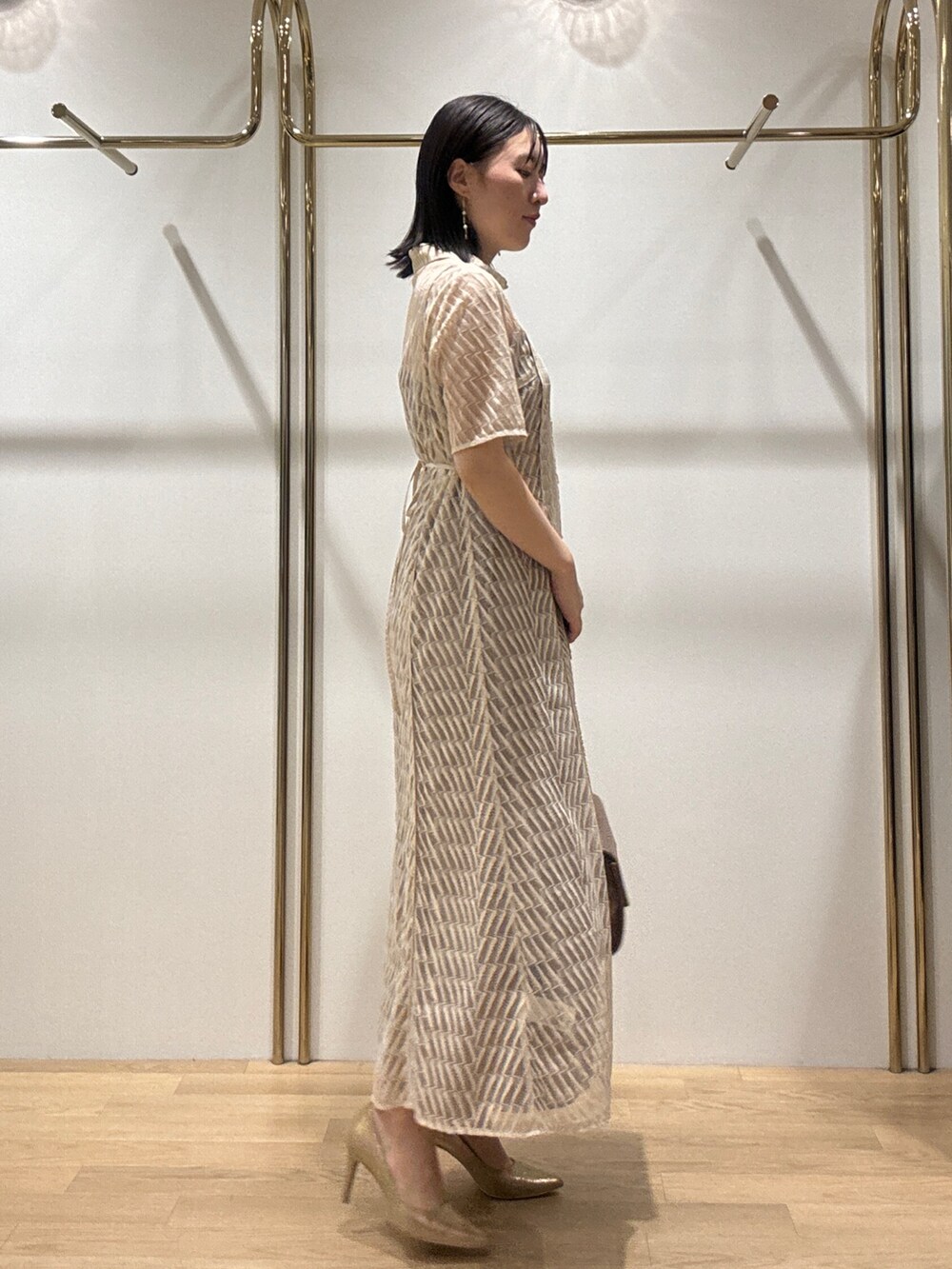 ゴールド系のハンドバッグ、ゴールド系のパンプス、ベージュ系のドレスを着用したレディースの秋コーディネートの2枚目の写真