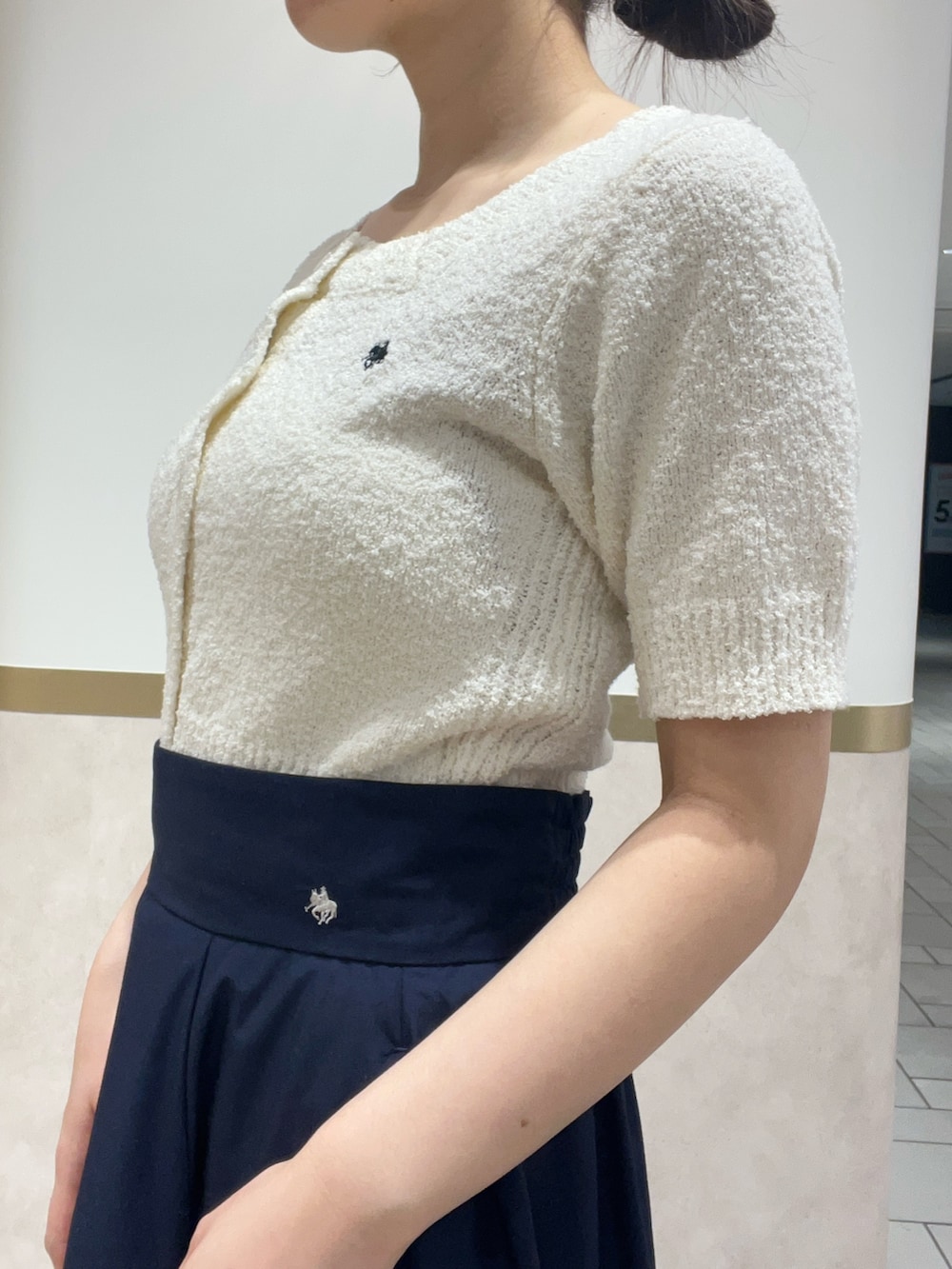 ブルー系のスカート、ホワイト系のニット/セーター、ブラック系のパンプスを着用したレディースの春コーディネートの6枚目の写真