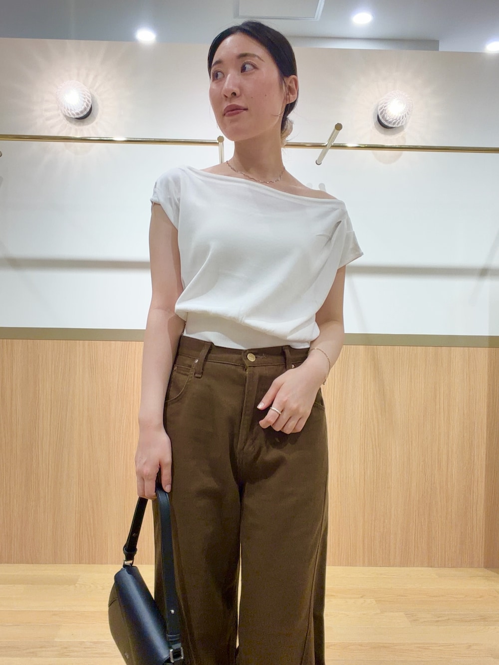 ブラウン系のデニムパンツ、オレンジ系のサンダル、ホワイト系のニット/セーターを着用したレディースの夏コーディネートの6枚目の写真