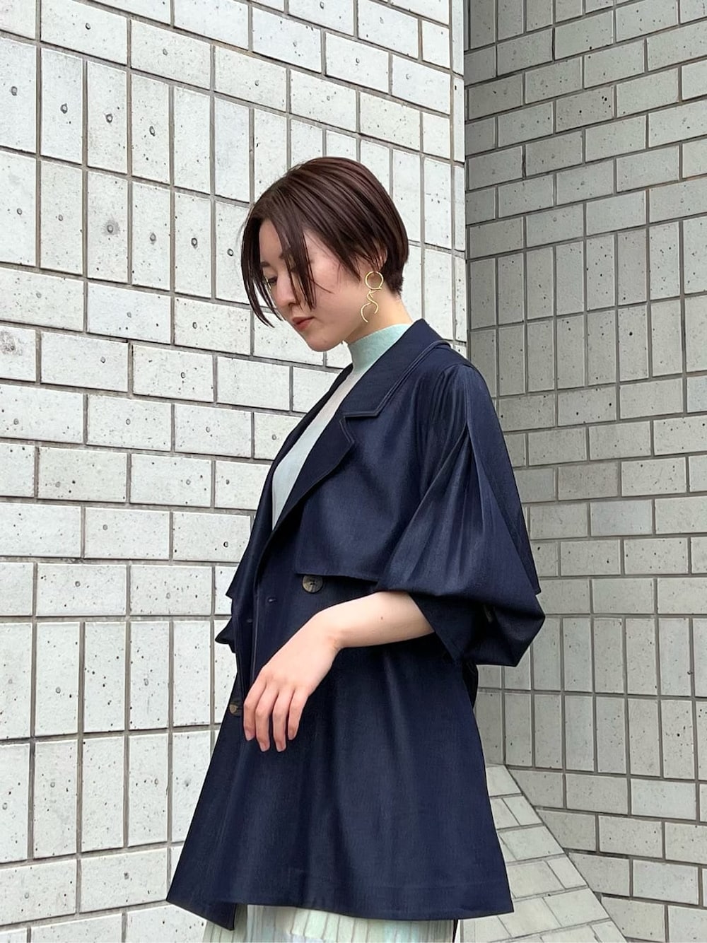 ベージュ系のブーツ、ブルー系のトレンチコート、グリーン系のワンピースを着用したレディースの春コーディネートの8枚目の写真