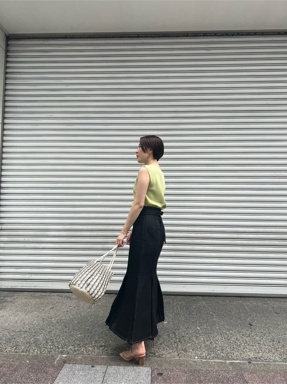 ブルー系のスカート、ベージュ系のサンダル、イエロー系のニット/セーターを着用したレディースの春コーディネートの2枚目の写真