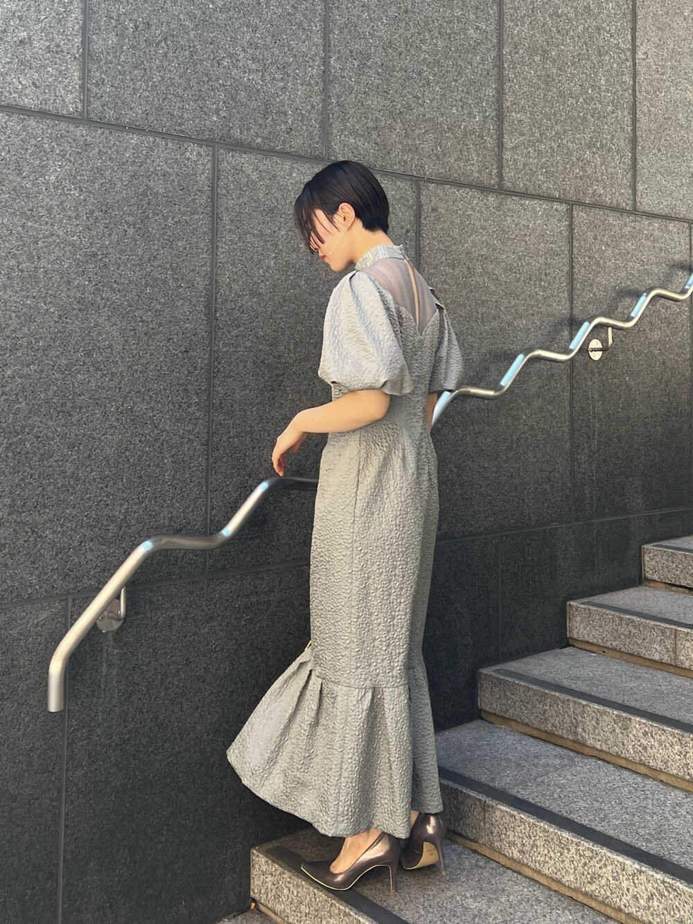 ブラック系のその他アウター、シルバー系のパンプス、グリーン系のドレスを着用したレディースの秋コーディネートの4枚目の写真