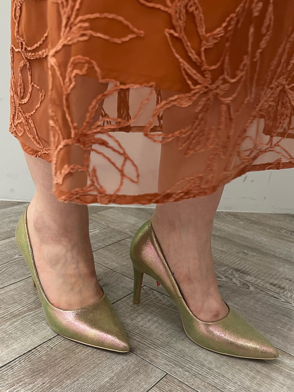 ゴールド系のパンプス、ゴールド系のハンドバッグ、オレンジ系のドレスを着用したレディースの夏コーディネートの9枚目の写真