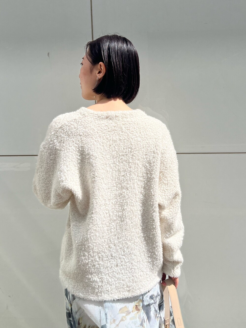 ホワイト系のパンプス、ベージュ系のハンドバッグ、ホワイト系のニット/セーターを着用したレディースの春コーディネートの5枚目の写真