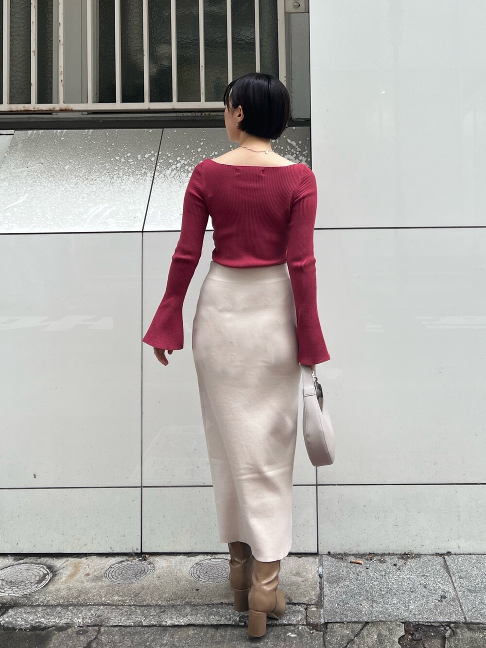 グレー系のノーカラーコート、ベージュ系のブーツ、ホワイト系のハンドバッグを着用したレディースの冬コーディネートの7枚目の写真