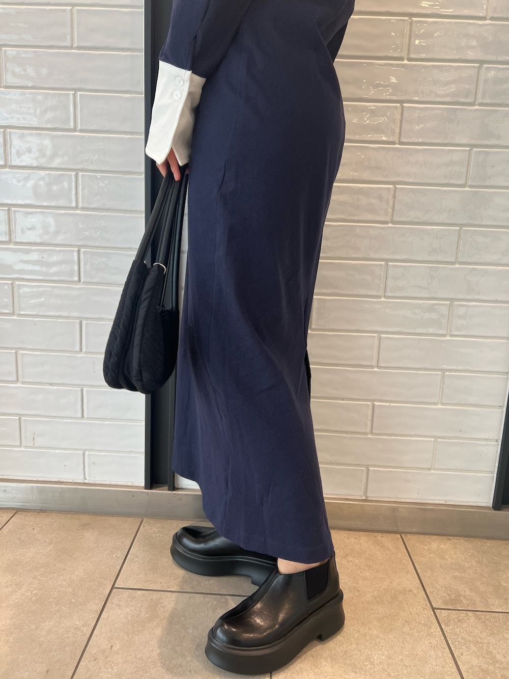 ブラック系のハンドバッグ、ブラック系のブーツ、ブルー系のワンピースを着用したレディースの秋コーディネートの7枚目の写真