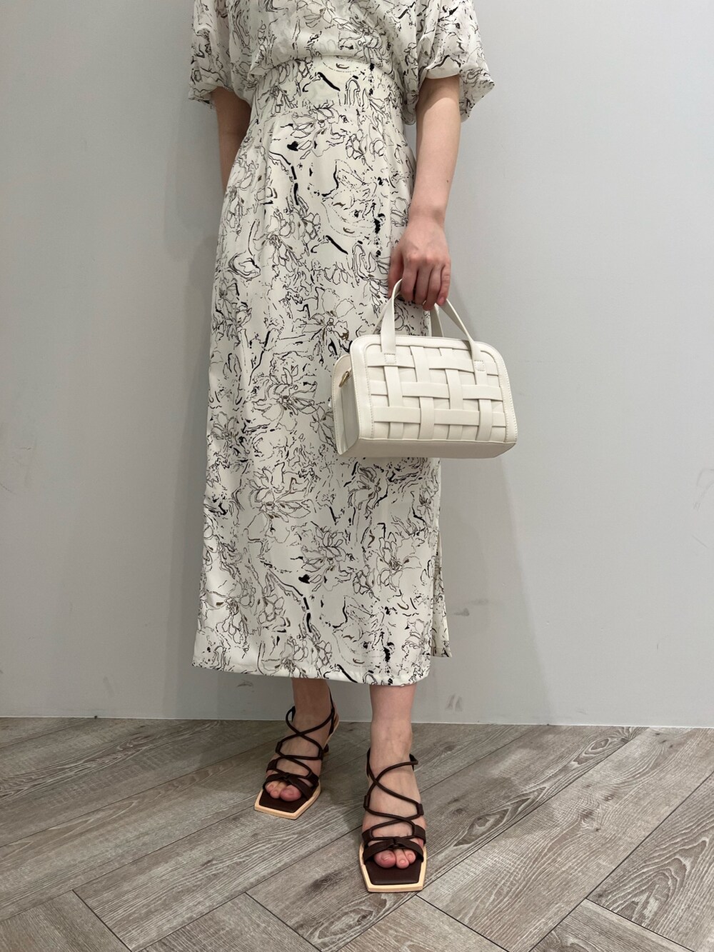 ブラウン系のサンダル、ホワイト系のショルダーバッグ、ホワイト系のワンピースを着用したレディースの春コーディネートの6枚目の写真