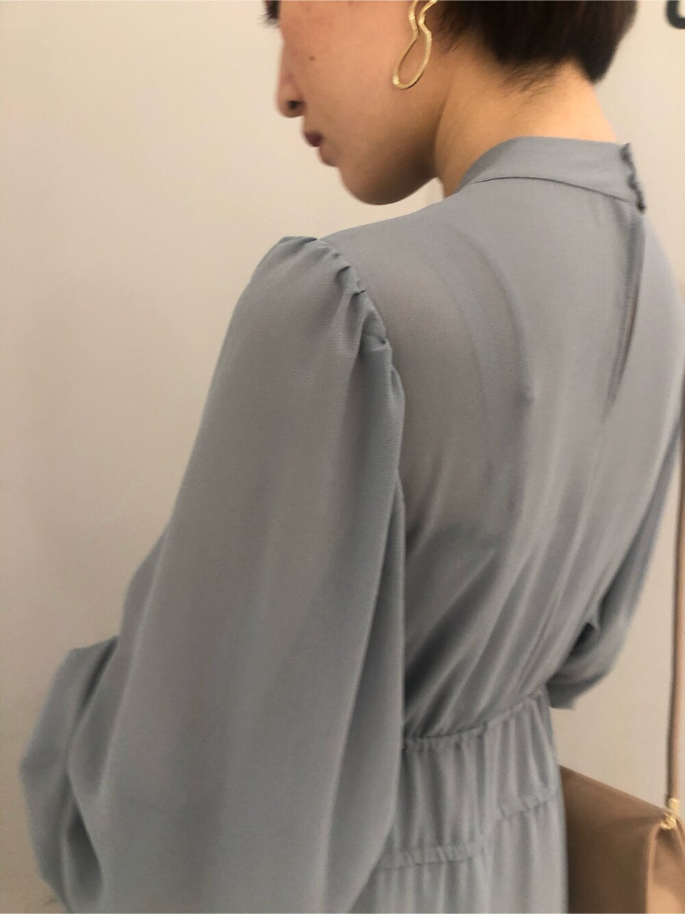 ベージュ系のハンドバッグ、ブルー系のワンピースを着用したレディースの冬コーディネートの3枚目の写真