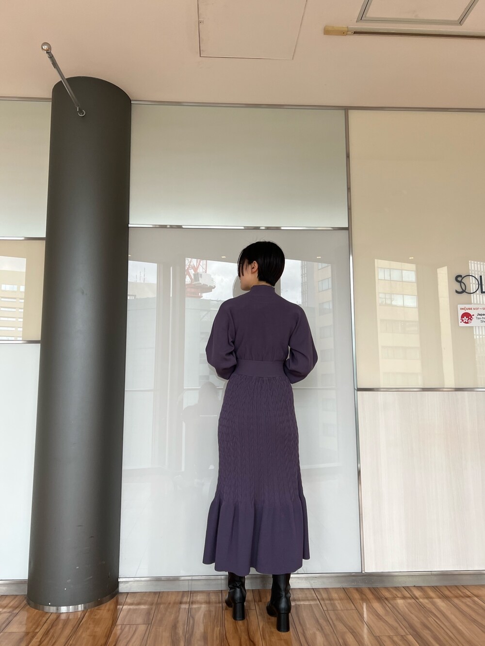 ブラック系のダウンジャケット/コート、ブラック系のブーツ、パープル系のワンピースを着用したレディースの冬コーディネートの9枚目の写真