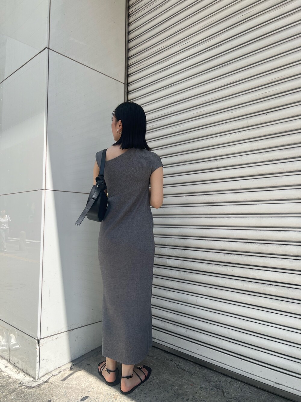 グレー系のワンピース、ブラック系のサンダル、ブラック系のショルダーバッグを着用したレディースの夏コーディネートの3枚目の写真