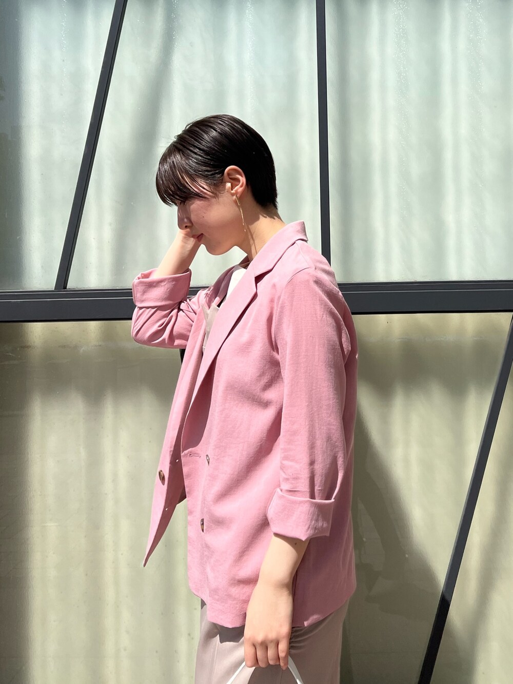 ベージュ系のワンピース、ピンク系のテーラードジャケット、ホワイト系のハンドバッグを着用したレディースの春コーディネートの3枚目の写真