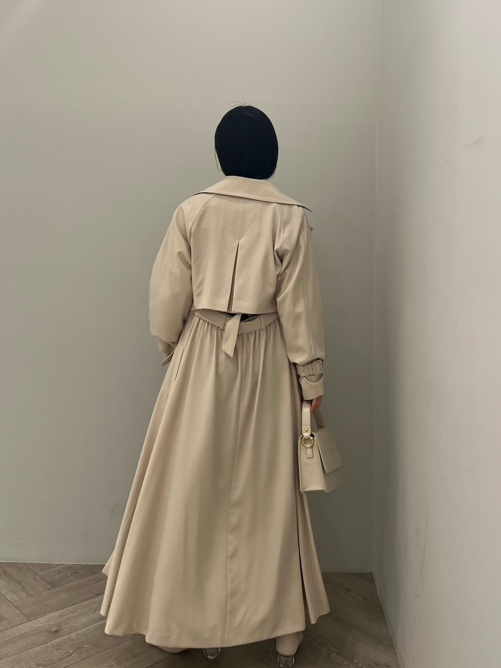 ホワイト系のトレンチコート、ホワイト系のニット/セーター、ブラック系のデニムパンツを着用したレディースの冬コーディネートの2枚目の写真