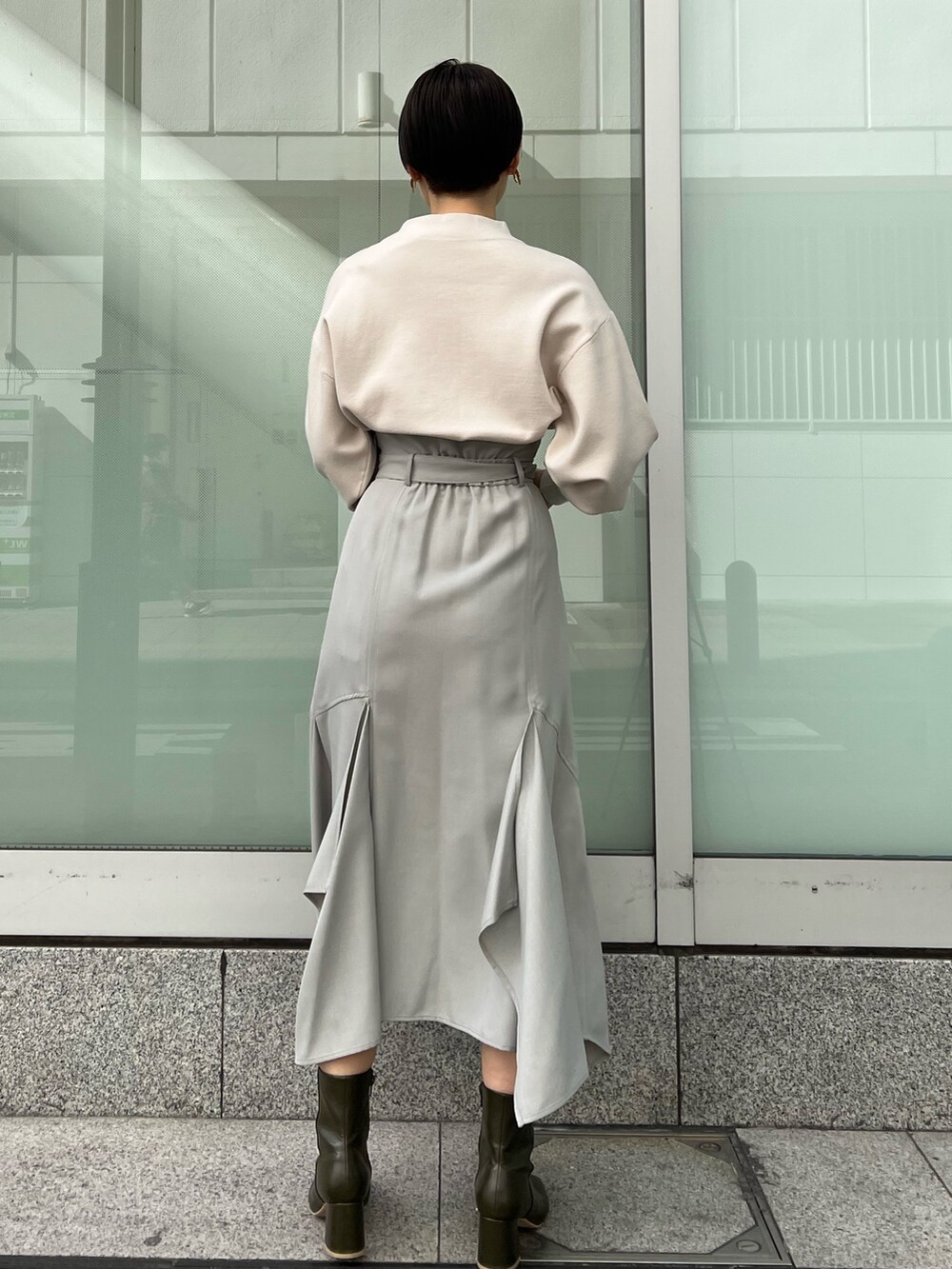 ベージュ系のブーツ、グリーン系のスカート、ホワイト系のニット/セーターを着用したレディースの冬コーディネートの3枚目の写真