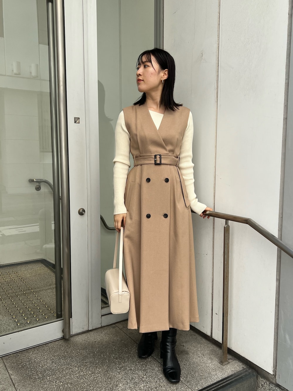 ベージュ系のトレンチコート、ホワイト系のショルダーバッグ、ホワイト系のニット/セーターを着用したレディースの秋コーディネートの6枚目の写真