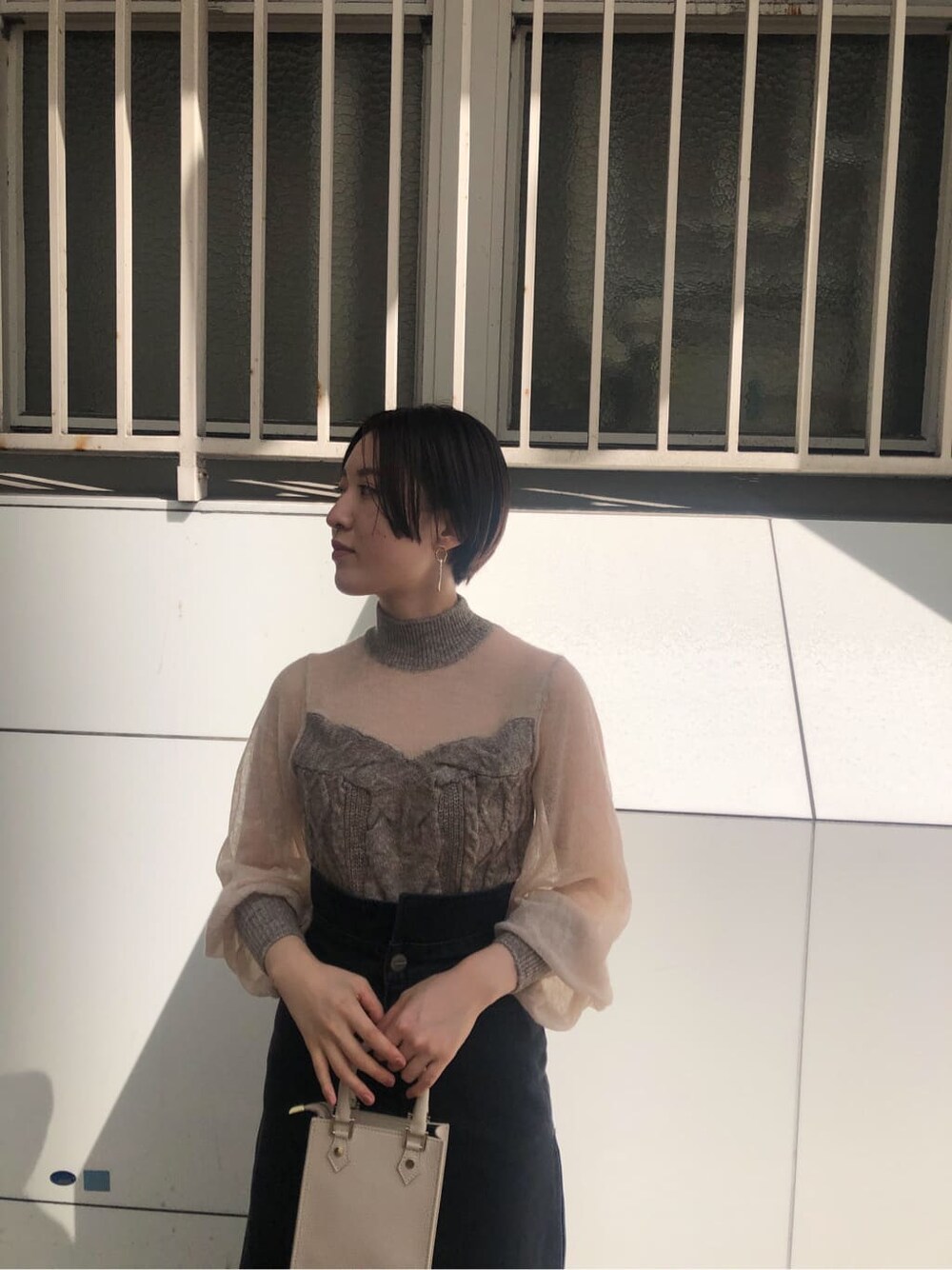 ベージュ系のブーツ、ホワイト系のショルダーバッグ、ブラック系のデニムスカートを着用したレディースの秋コーディネートの4枚目の写真