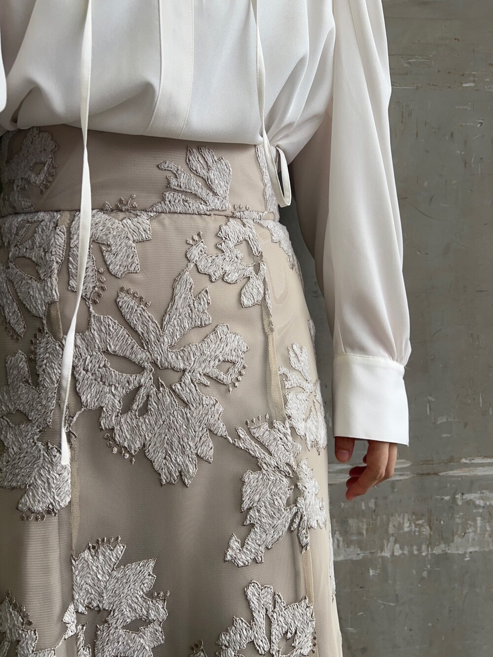 ベージュ系のスカート、ホワイト系のシャツ/ブラウス、ゴールド系のピアス(両耳用)を着用したレディースの秋コーディネートの6枚目の写真