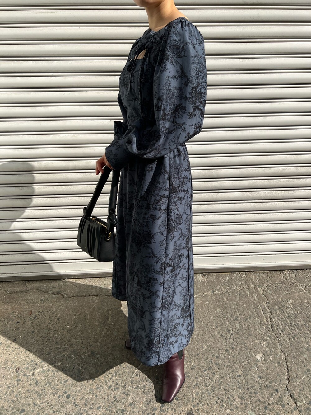 レッド系のブーツ、ブラック系のノーカラーコート、ブルー系のワンピースを着用したレディースの冬コーディネートの8枚目の写真