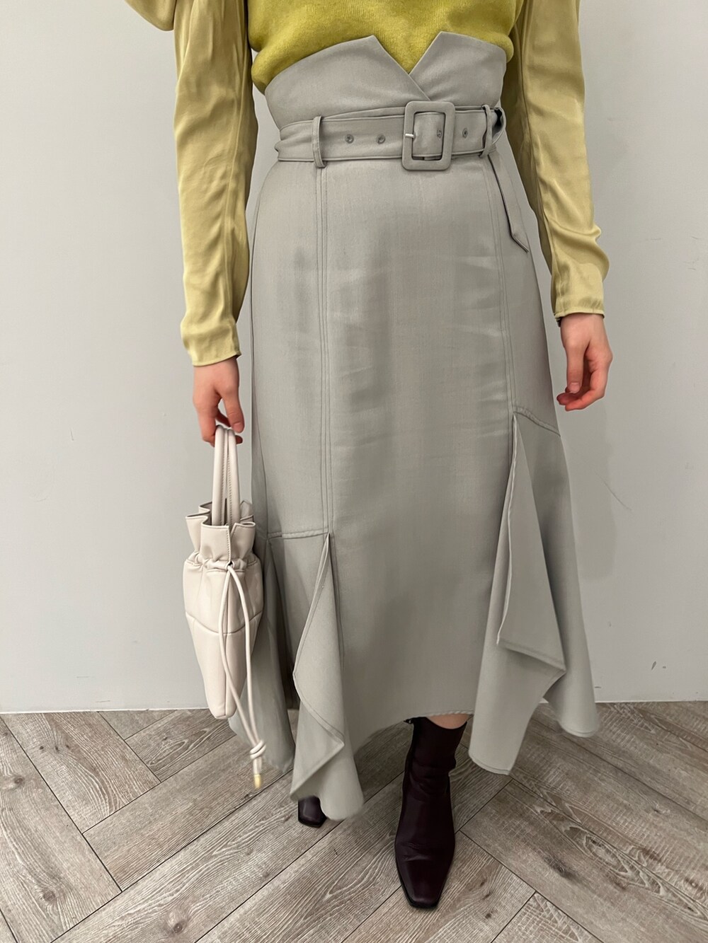 ブラック系のブーツ、ホワイト系のハンドバッグ、グリーン系のスカートを着用したレディースの冬コーディネートの7枚目の写真