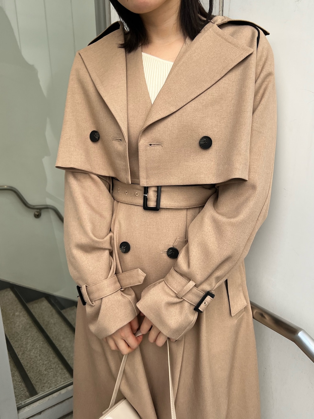 ベージュ系のトレンチコート、ホワイト系のショルダーバッグ、ホワイト系のニット/セーターを着用したレディースの秋コーディネートの4枚目の写真