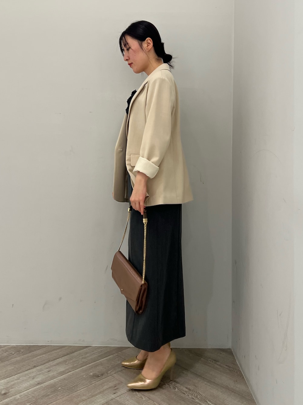 ゴールド系のパンプス、グレー系のドレス、ベージュ系のテーラードジャケットを着用したレディースの秋コーディネートの2枚目の写真