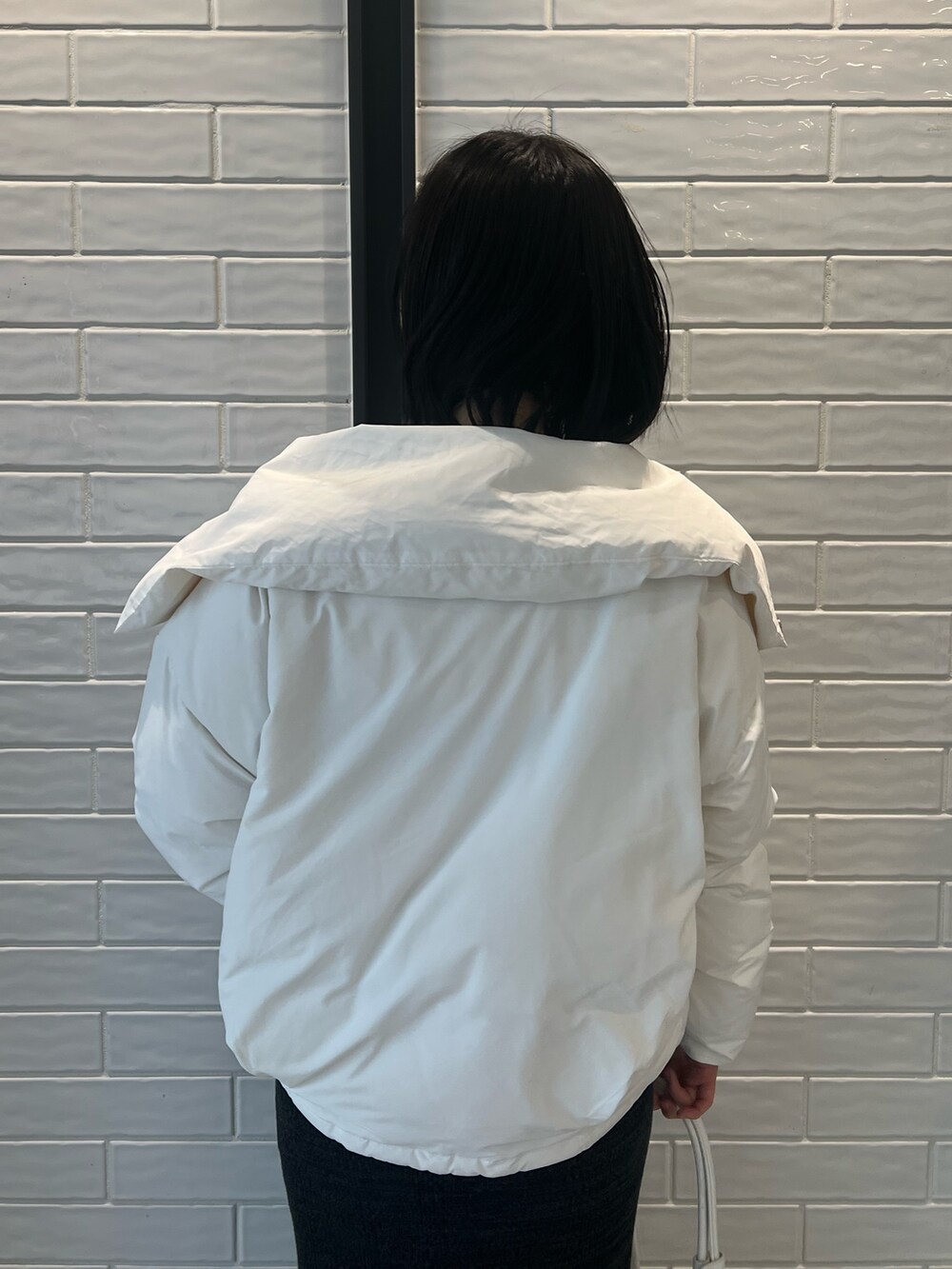 ホワイト系のダウンジャケット/コート、ブラック系のワンピース、ブラック系のブーツを着用したレディースの冬コーディネートの4枚目の写真