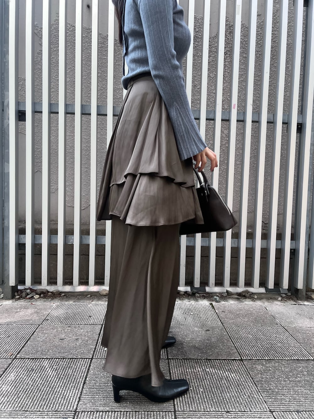 ブルー系のニット/セーター、ブラウン系のスカート、ブラック系のブーツを着用したレディースの秋コーディネートの6枚目の写真