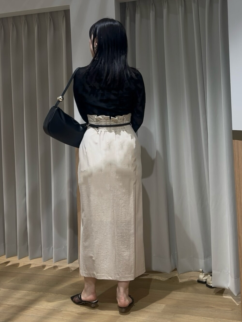 ブラック系のニット/セーター、ベージュ系のスカート、ブラック系のサンダルを着用したレディースの春コーディネートの3枚目の写真