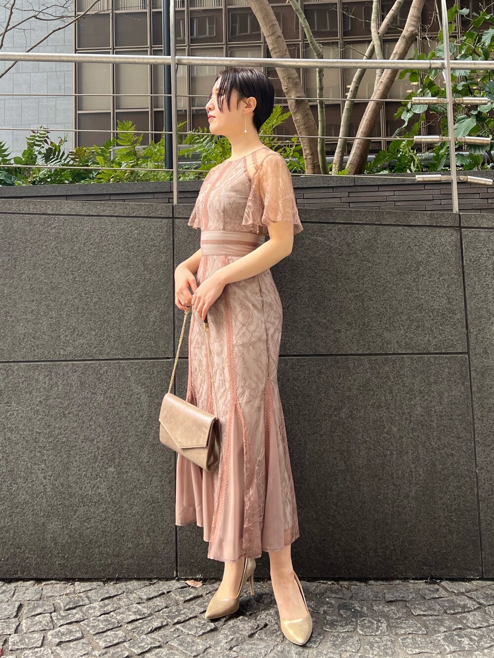ゴールド系のハンドバッグ、ゴールド系のパンプス、ベージュ系のノーカラーコートを着用したレディースの冬コーディネートの8枚目の写真