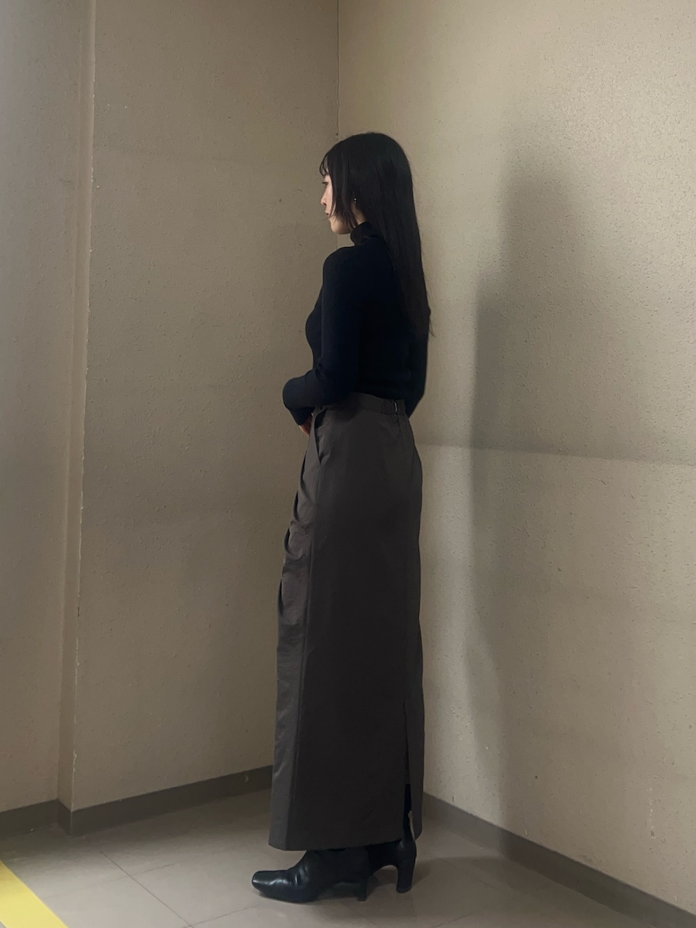 ブラック系のブーツ、ブラック系のニット/セーター、ブラウン系のスカートを着用したレディースの秋コーディネートの2枚目の写真