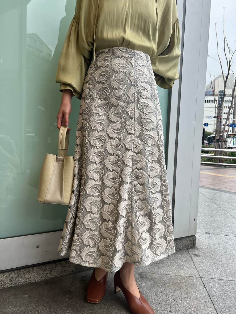 ホワイト系のハンドバッグ、ホワイト系のパンプス、グリーン系のシャツ/ブラウスを着用したレディースの春コーディネートの4枚目の写真