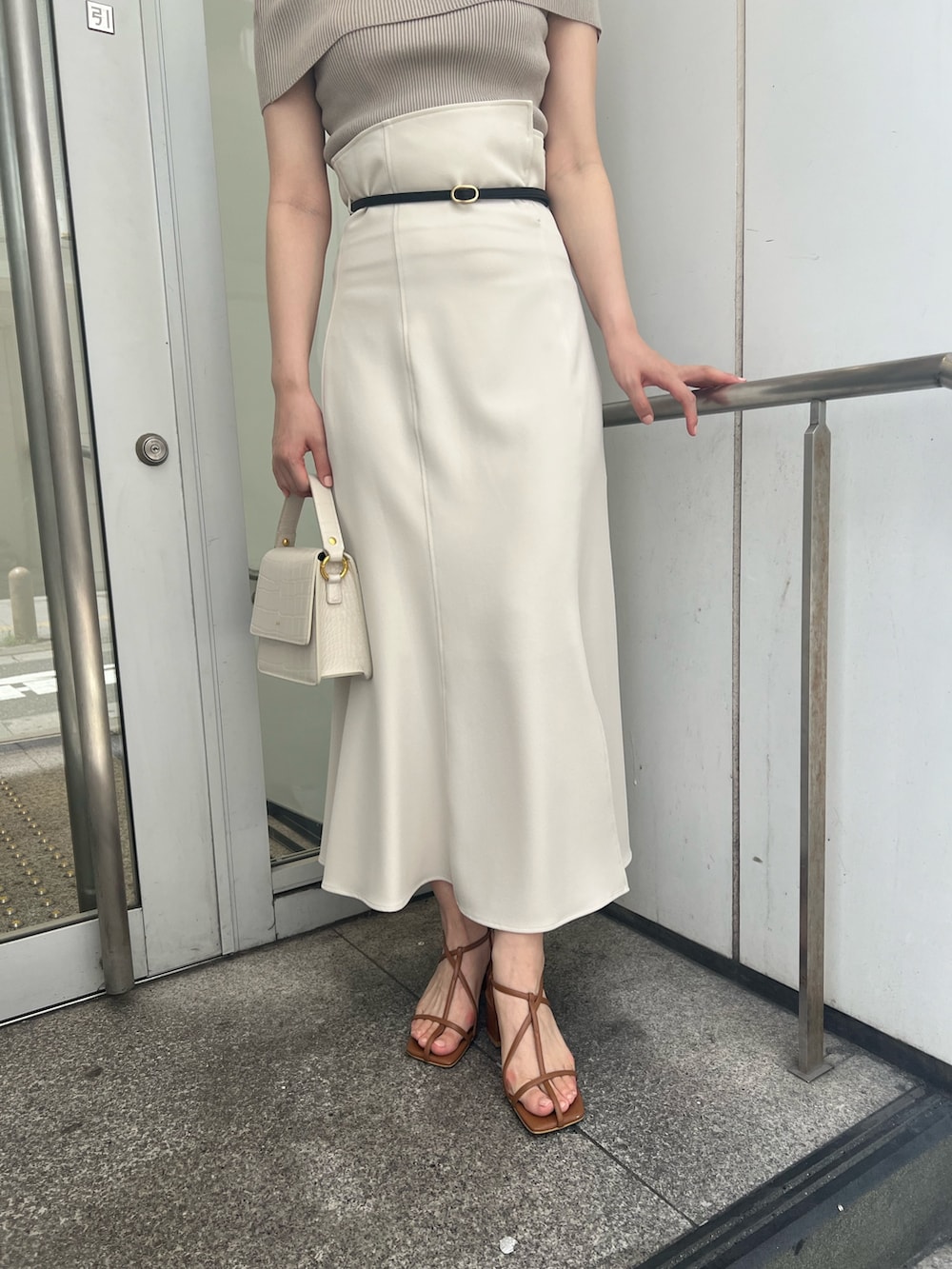 ホワイト系のショルダーバッグ、ホワイト系のスカート、ベージュ系のニット/セーターを着用したレディースの夏コーディネートの6枚目の写真