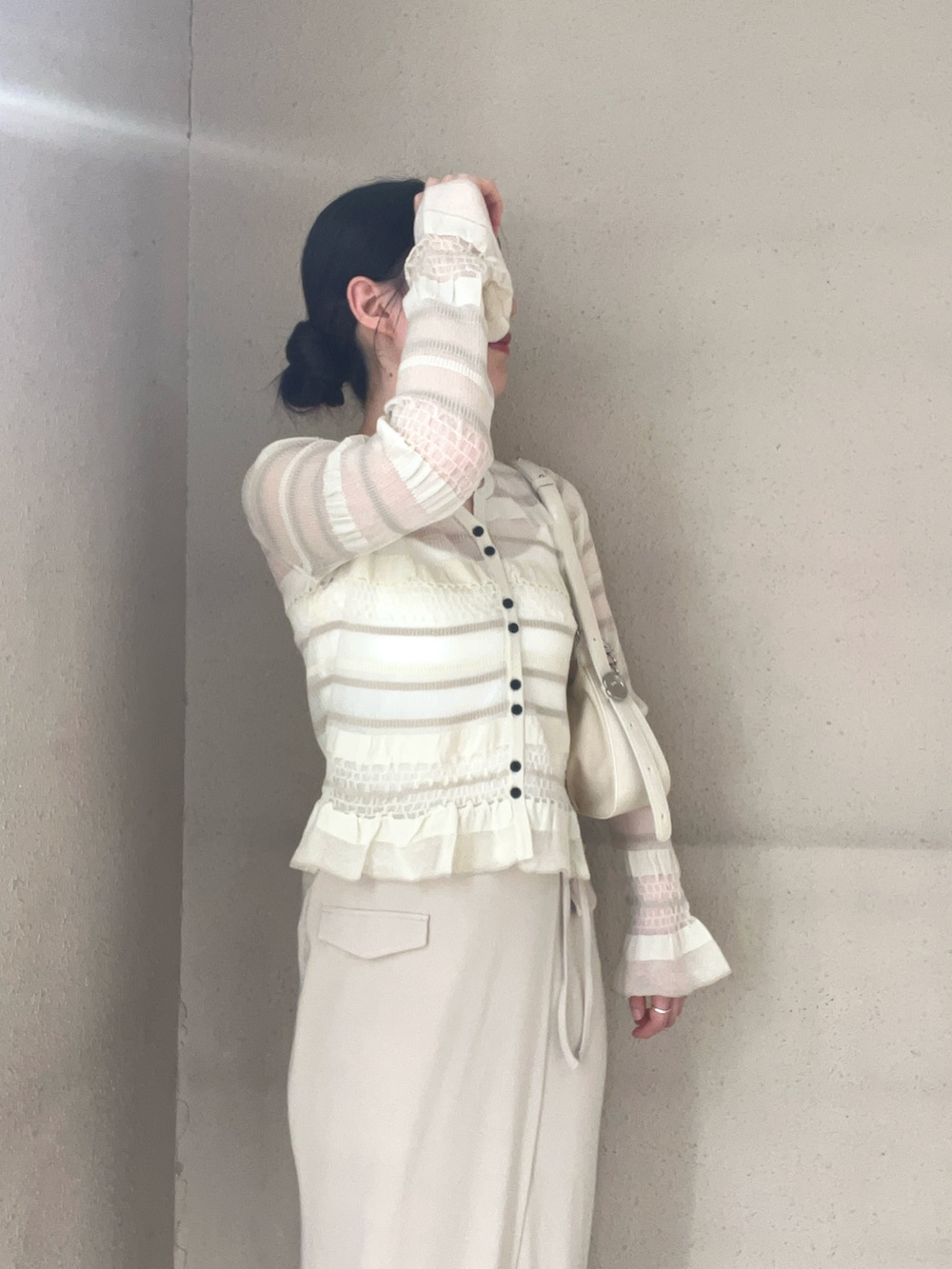 ベージュ系のスカート、ホワイト系のニット/セーター、ホワイト系のスニーカーを着用したレディースの春コーディネートの4枚目の写真