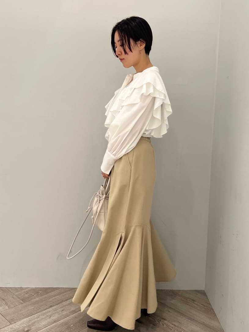 ベージュ系のスカート、レッド系のブーツ、ホワイト系のハンドバッグを着用したレディースの秋コーディネートの2枚目の写真