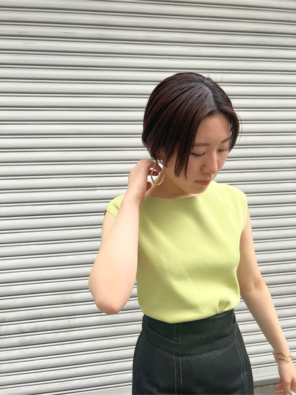 ブルー系のスカート、ベージュ系のサンダル、イエロー系のニット/セーターを着用したレディースの春コーディネートの5枚目の写真