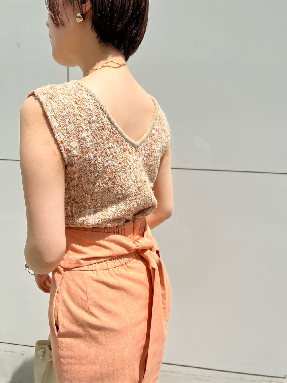 ホワイト系のハンドバッグ、オレンジ系のスカート、その他のパンプスを着用したレディースの春コーディネートの7枚目の写真