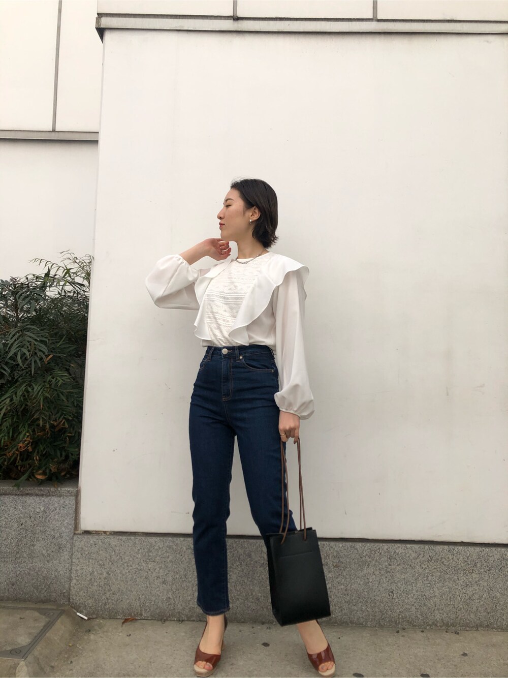 ブルー系のデニムパンツ、ブラック系のハンドバッグ、ブラウン系のパンプスを着用したレディースの春コーディネートの4枚目の写真