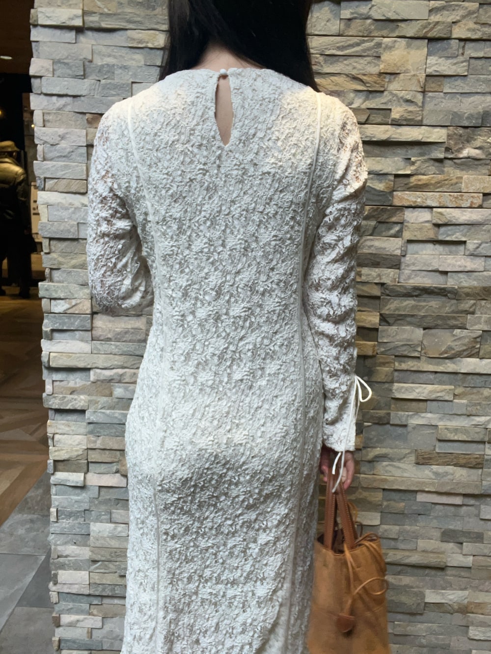 ホワイト系のワンピース、ブラウン系のハンドバッグ、シルバー系のパンプスを着用したレディースの冬コーディネートの5枚目の写真