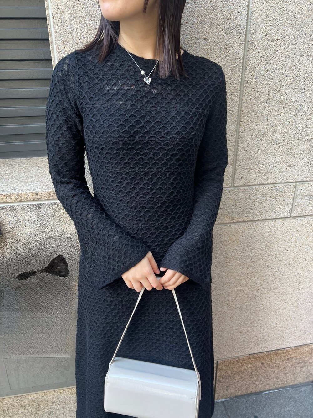 ブラック系のブーツ、ブラック系のワンピース、ホワイト系のショルダーバッグを着用したレディースの秋コーディネートの2枚目の写真