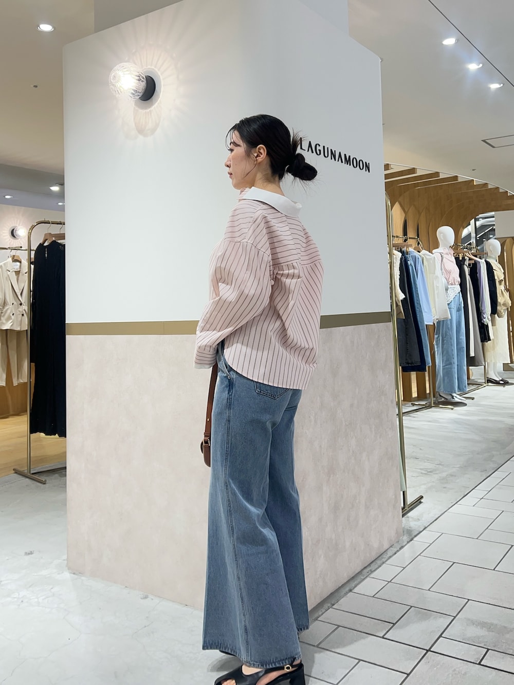 ピンク系のシャツ/ブラウス、ブルー系のデニムパンツ、ブラウン系のハンドバッグを着用したレディースの春コーディネートの2枚目の写真